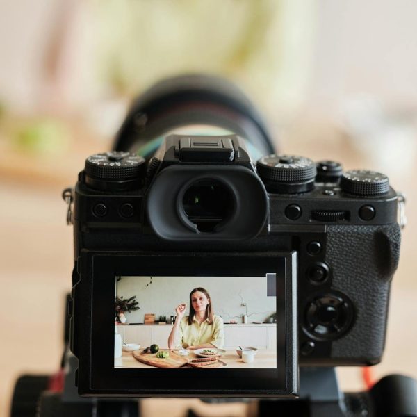 Hegazy Web Caucasian woman vlogging at home with camera in a kitchen setting, captured indoors.